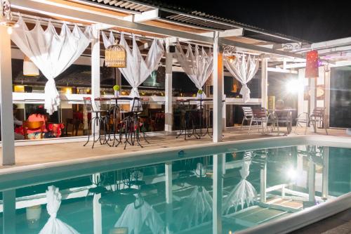 una piscina con sillas, una mesa y un bar en Hotel Cravo e Canela, en Campos dos Goytacazes