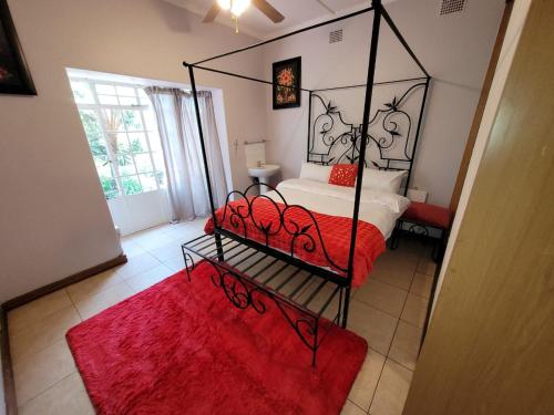 Schlafzimmer mit einem Himmelbett und einem roten Teppich in der Unterkunft Van Buuren Lodge in Germiston