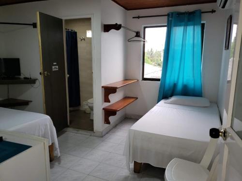 een kamer met 2 bedden en een badkamer met een raam bij Posada Doña Rosa in San Andrés