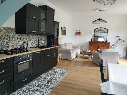 une cuisine avec des armoires noires et un salon dans l'établissement Les bords de Rance, à Dinan