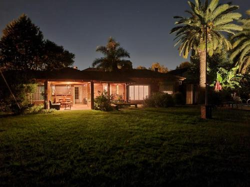 a house with a palm tree in front of a yard at Nagual B&B - Airport Shuttle in Tristán Suárez