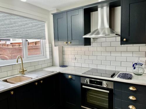 cocina con armarios negros, fregadero y ventana en Canada House - Sleeps 6 -3 King or 6 Single Ideal for contractors, en Warrington