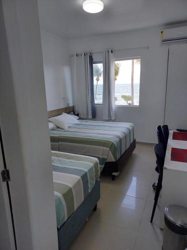 two beds in a room with a window at Marinas Tamandaré Flat in Tamandaré