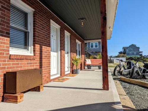 a brick building with a porch with a bench and motorcycles at Tower Circle Motel in Buxton