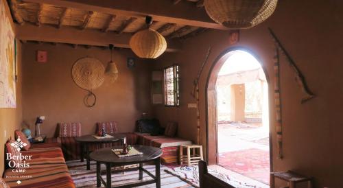 sala de estar con 2 mesas y puerta abierta en Berber Oasis Camp, en Oulad Driss