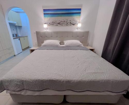 ATHANASIA APARTMENTS في مدينة سكياثوس: غرفة نوم بسرير كبير عليها لوحة على الحائط