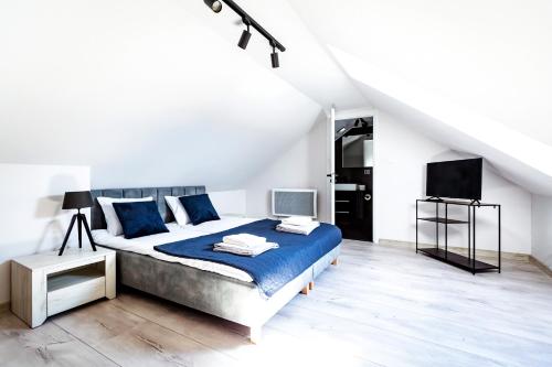 a white bedroom with a bed and a tv at AWO Apartamenty in Łeba