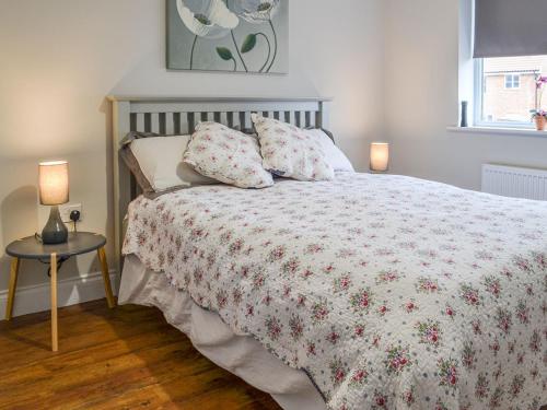 a bedroom with a bed with a floral bedspread and two lamps at Lapwing Lodge in New Hunstanton
