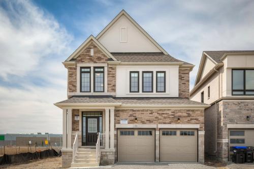 a house with two garage doors in front of it at Unwind Here in a Stylish and Cozy Space in Bradford