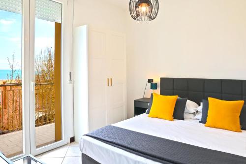 里米尼的住宿－APPARTAMENTI LEONE - Vista Mare Rimini，一间卧室配有一张带黄色枕头的床和一个阳台