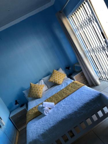a blue bedroom with a bed with a window at Pozi Guest House in Sasolburg