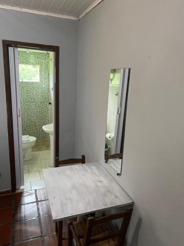 uma casa de banho com uma mesa, um WC e um espelho. em Pousada do colono em Morretes
