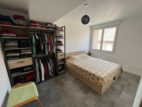 um quarto com uma cama e uma prateleira de roupas em Lumineux, centre-ville d’Oyonnax, à 2 pas des lacs em Oyonnax