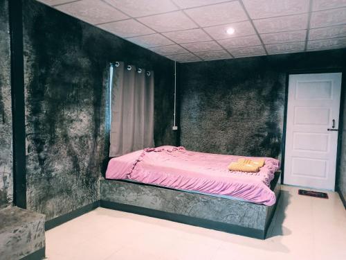 Dormitorio con cama rosa en una pared negra en Pai Forest Resort, en Pai