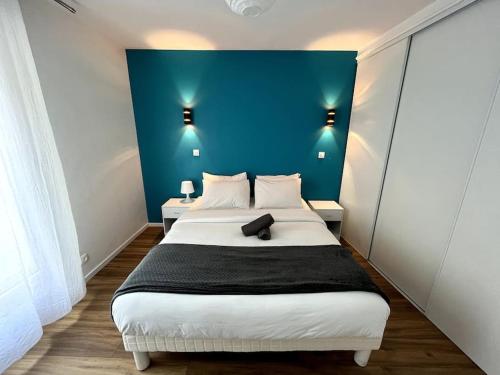 une chambre avec un grand lit avec un mur bleu dans l'établissement Moderne appartement - Gare - centre-ville, au Mans