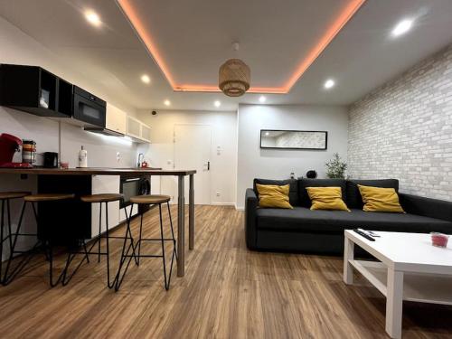 un salon avec un canapé noir et une cuisine dans l'établissement Moderne appartement - Gare - centre-ville, au Mans