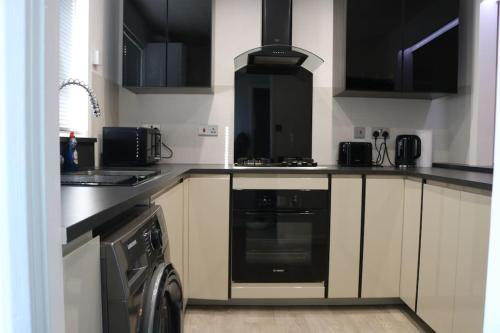 a kitchen with a stove and a washer in it at Lovely flat with Wi-Fi and free parking in Reading