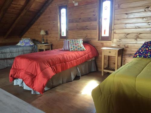 ein Schlafzimmer mit einem roten Bett in einer Holzhütte in der Unterkunft CABAÑAS ALMA SERENA in Capilla del Monte