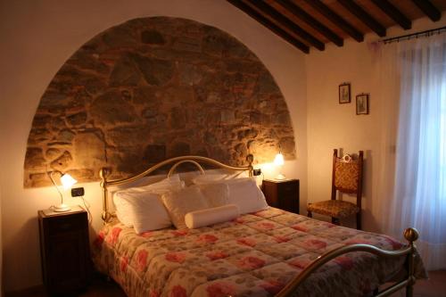 a bedroom with a bed with a stone wall at Antico Casale Pozzuolo in Seggiano