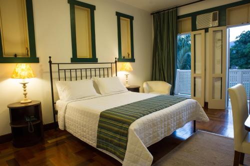 a bedroom with a bed and two lamps and a window at Don Quixote Pousada in Tiradentes