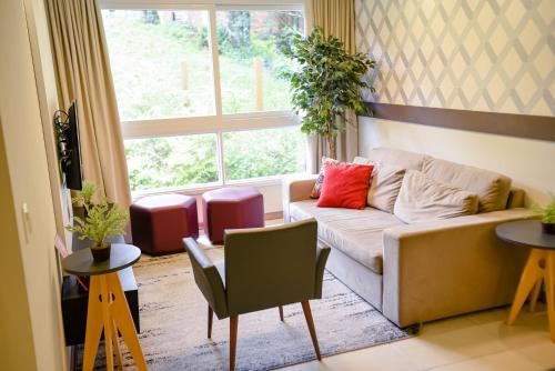 - un salon avec un canapé et une fenêtre dans l'établissement Incrível Apto De 2 Quartos Em Gramado - Ed Paradiso, à Gramado
