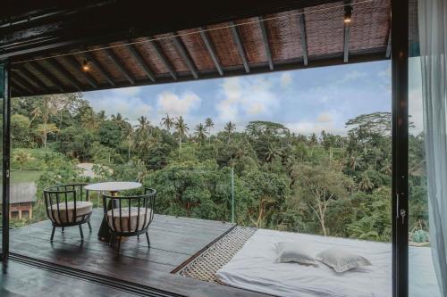 a balcony with a bed and a table and chairs at Villa Cella Bella Ubud in Ubud