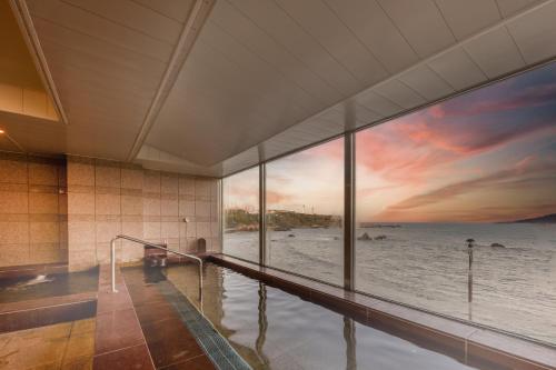 a room with a bath tub with a view of the ocean at 銚子グランドホテル in Choshi