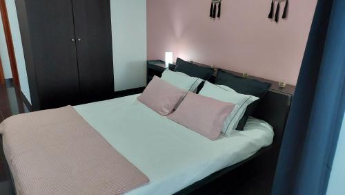 a bedroom with a bed with two pink pillows at Retiro das Camélias in Lajes das Flores