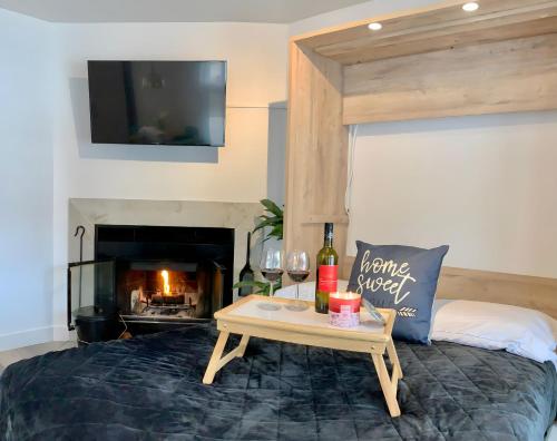 a bed with a table with wine bottles and a tv at Le Loft du Loch - Condo près du lac et des montagnes! in Magog-Orford