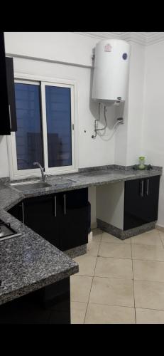 a kitchen with a counter and a sink and two windows at Appartement à beni mellal in Beni Mellal