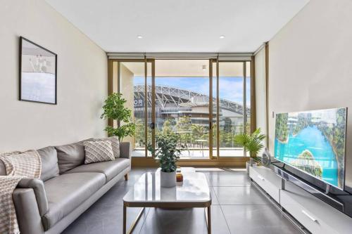 a living room with a couch and a tv at Olympic Park Stadium Cozy 1 bedroom Apt in Sydney