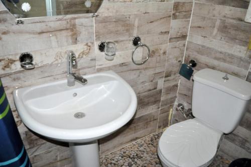 uma casa de banho com um lavatório branco e um WC. em Misteri em Esna