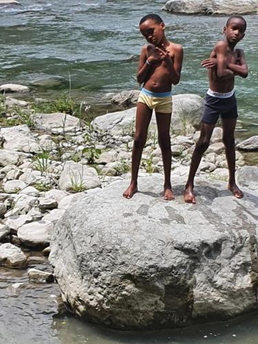 two boys standing on a rock by the water at Caribbean estate deluxe 2 in Portmore