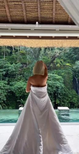 a woman in a wedding dress looking out a window at Villa Cella Bella Ubud in Ubud