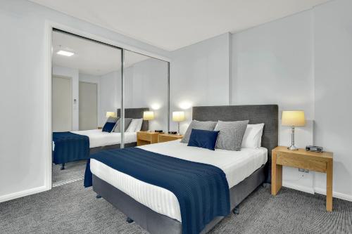 a hotel room with two beds and a mirror at North Sydney Large Two Bedroom MIL2302 in Sydney