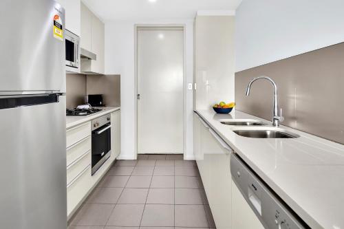 a white kitchen with a sink and a refrigerator at North Sydney Large Two Bedroom MIL2302 in Sydney