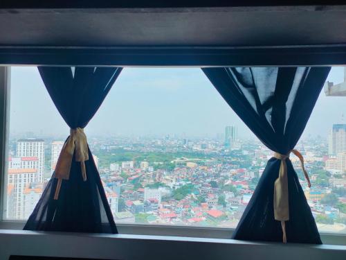 a window with blue curtains and a city view at Studio type Good for 2 Near Megamall in Manila