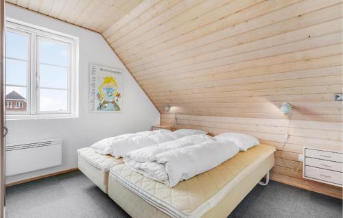 a bed in a room with a wooden wall at Cozy Home In Rm With House Sea View in Rømø Kirkeby