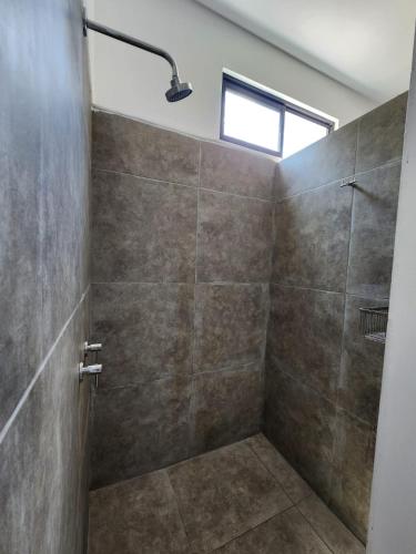 a bathroom with a shower with a glass door at Las Hamacas in Canoas De Punta Sal