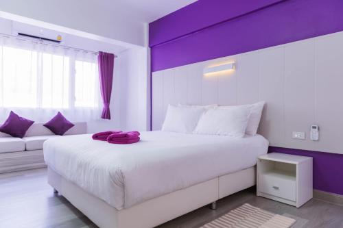 a bedroom with a large white bed with purple accents at Hotel Zing in Pattaya South