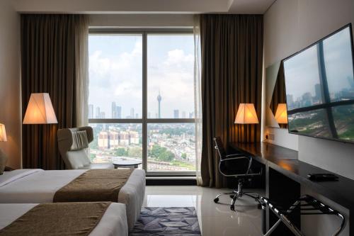 una camera d'albergo con due letti, una scrivania e una grande finestra di Orion City Hotel a Colombo