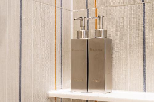 two silver bottles on a shelf in a bathroom at Jongno Olive Hotel in Seoul