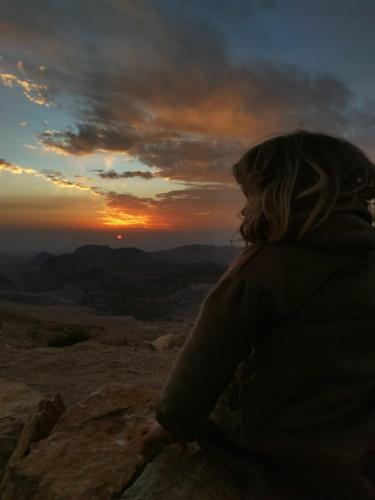 a woman sitting on a rock looking at the sunset at Petra Desert Dream Hotel in Wadi Musa