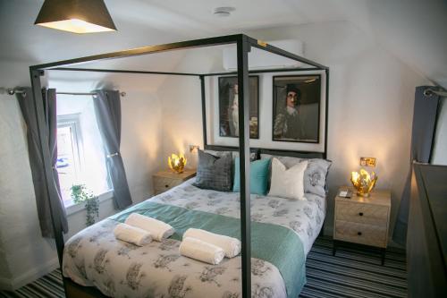 a bedroom with a canopy bed with two pillows at The Swan in Shepton Mallet