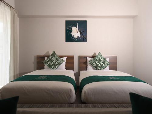 um quarto com duas camas e uma foto na parede em HOTEL Y'RISE TO URASOE em Urazoe