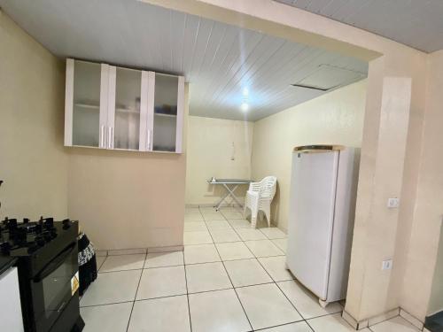Una cocina con un refrigerador y una mesa dentro. en Casa Grande com 2 quartos e 1 suíte, en Foz do Iguaçu