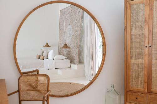 a mirror in a room with a bed and a chair at Amaka Villas in Uluwatu