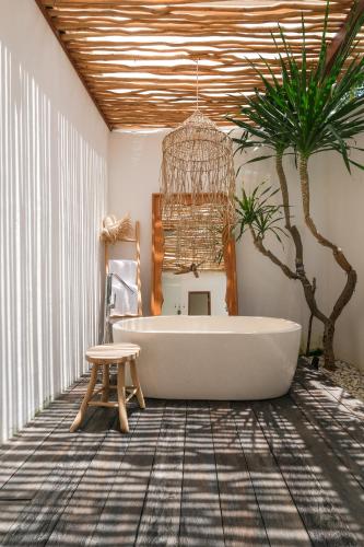 a bathroom with a tub and a palm tree at Amaka Villas in Uluwatu