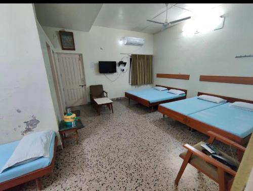 um quarto com três camas e uma tv nele em Reva Prabhu Sadan em Ambaji