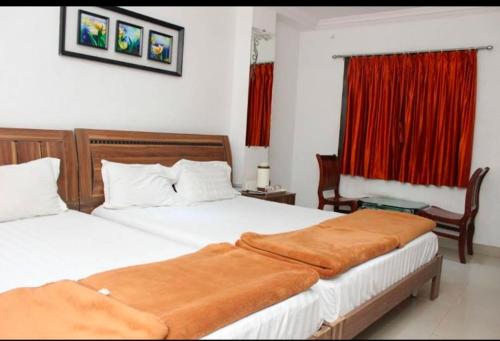 um quarto com 2 camas e uma janela com cortinas vermelhas em Reva Prabhu Sadan em Ambaji